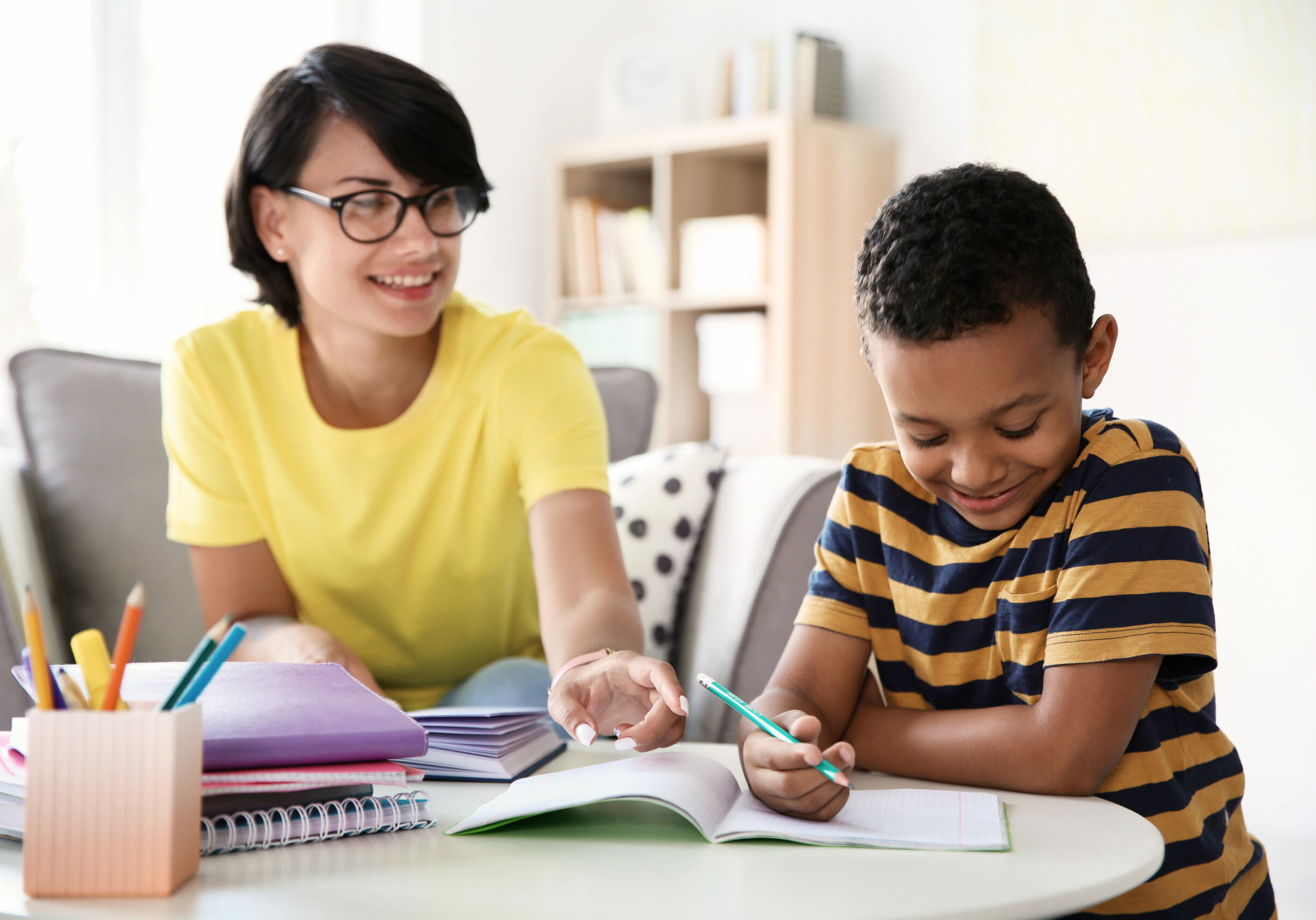 Young woman helping her child with homework at home. Elementary school Young woman helping her child with homework at home. Elementary school